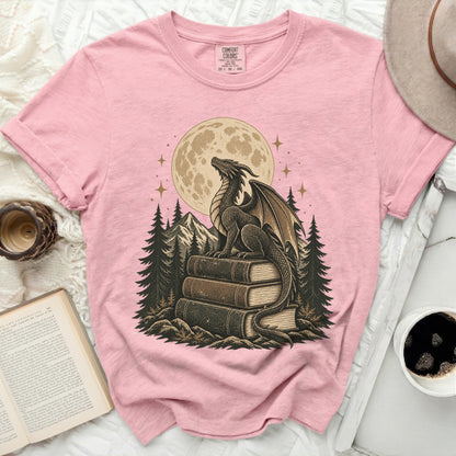 Pink t-shirt with dragon on books graphic under a moon and stars.