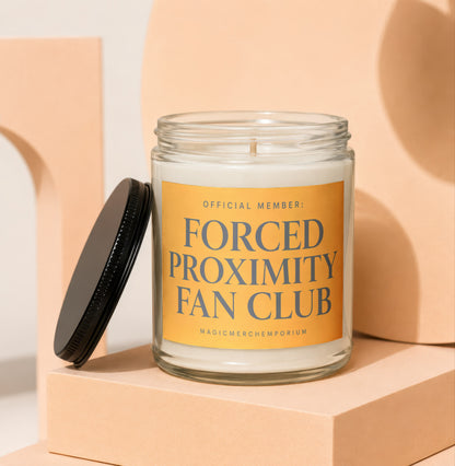 Glass jar candle with orange label reading "OFFICIAL MEMBER: FORCED PROXIMITY FAN CLUB".