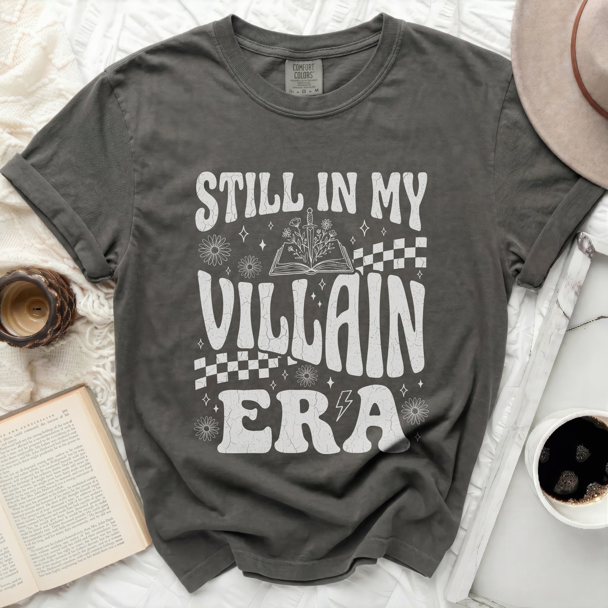 Still in my villain era graphic tee with book and sword design.