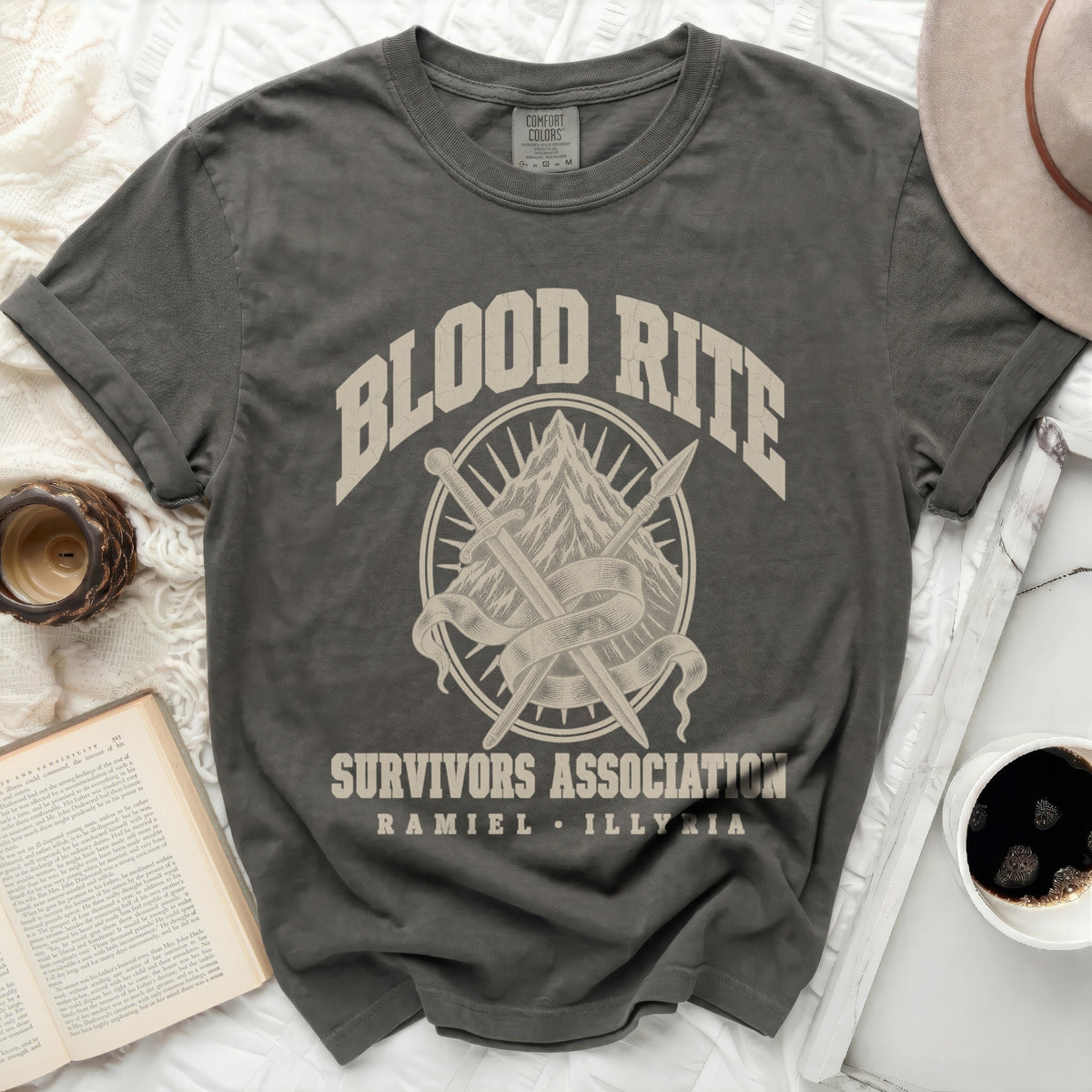 Charcoal crewneck t-shirt featuring the text "BLOOD RITE SURVIVORS ASSOCIATION RAMIEL ILLYRIA" and crossed swords over a mountain graphic.