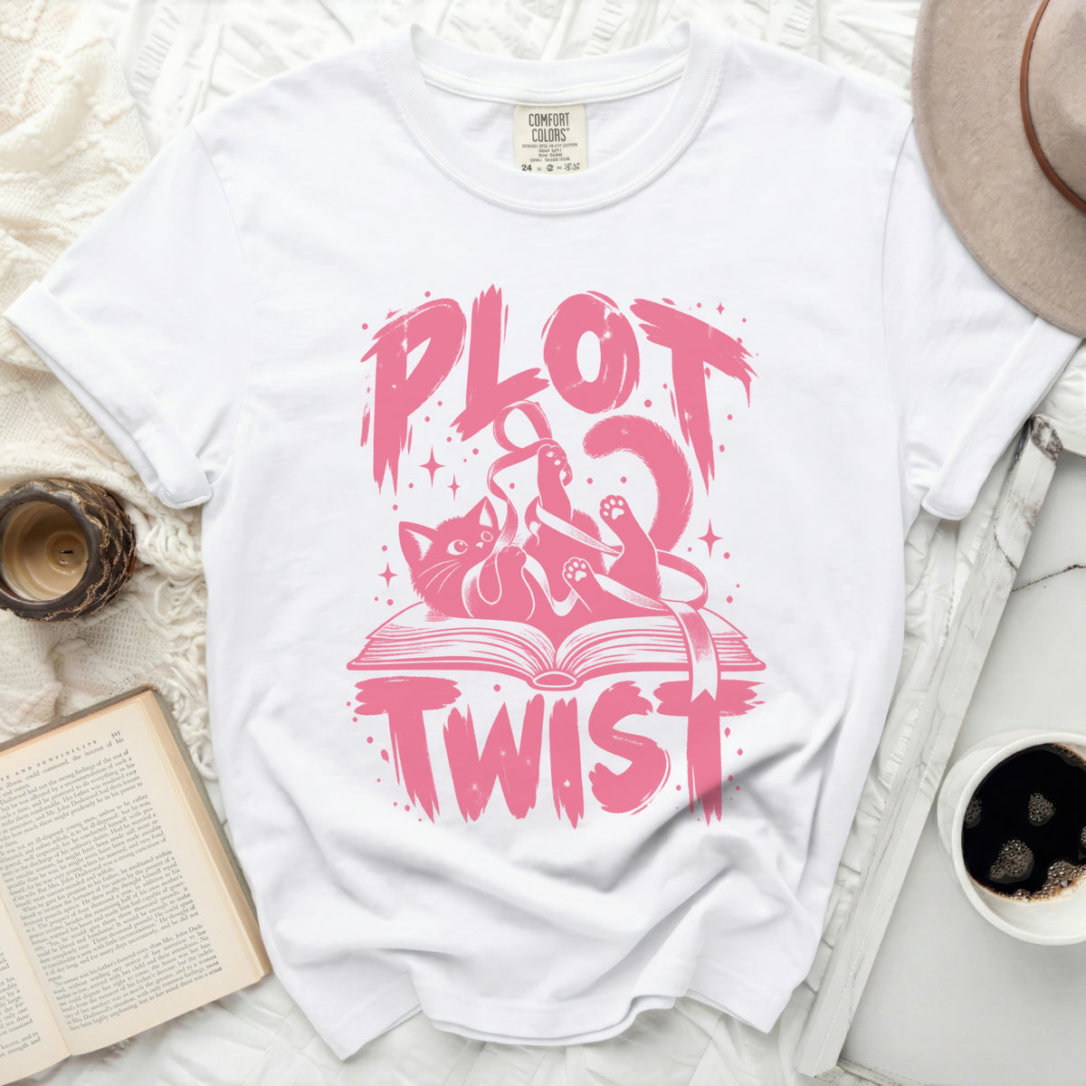 White t-shirt with pink "PLOT TWIST" text featuring a cat and an open book.