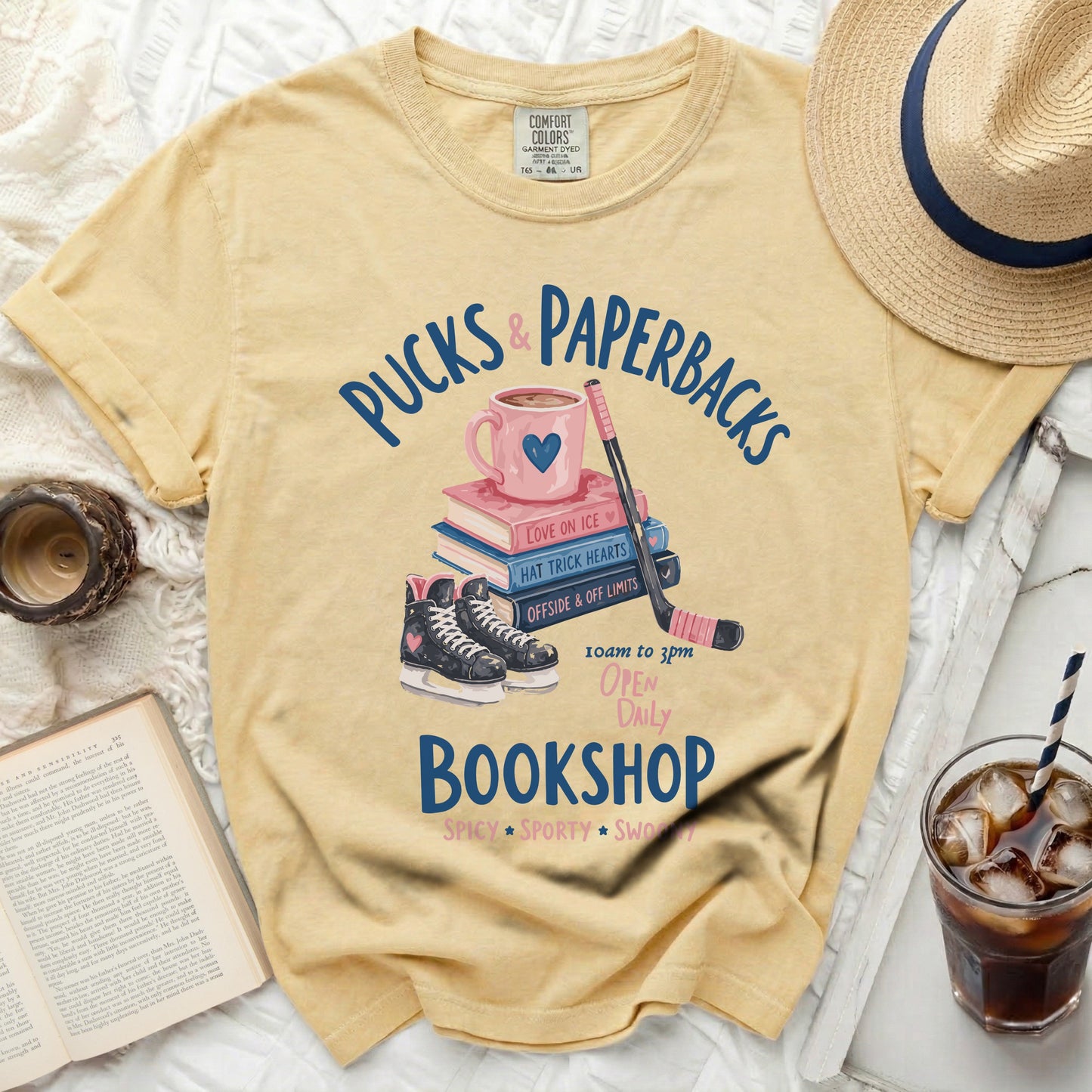 Yellow t-shirt with "Pucks & Paperbacks Bookshop" graphic and hockey elements.