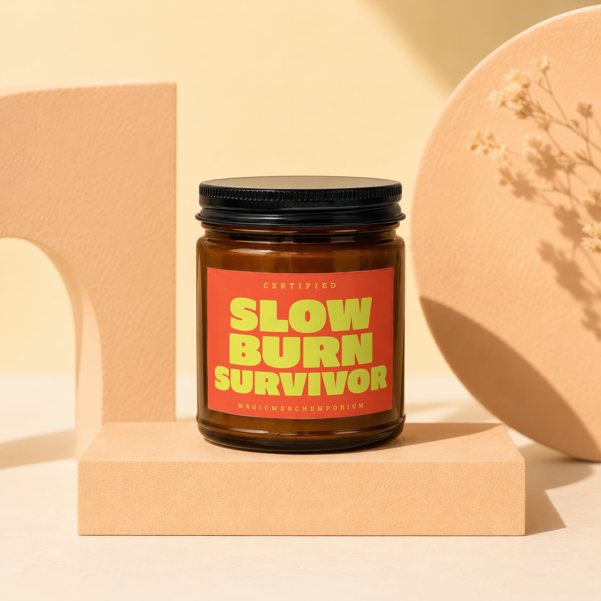 Amber jar candle with a red label reading "CERTIFIED SLOW BURN SURVIVOR MAGICMERCH...EMPORIUM".