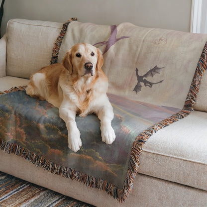 A golden retriever dog is sitting on a couch, with a dragon-themed blanket on the couch.