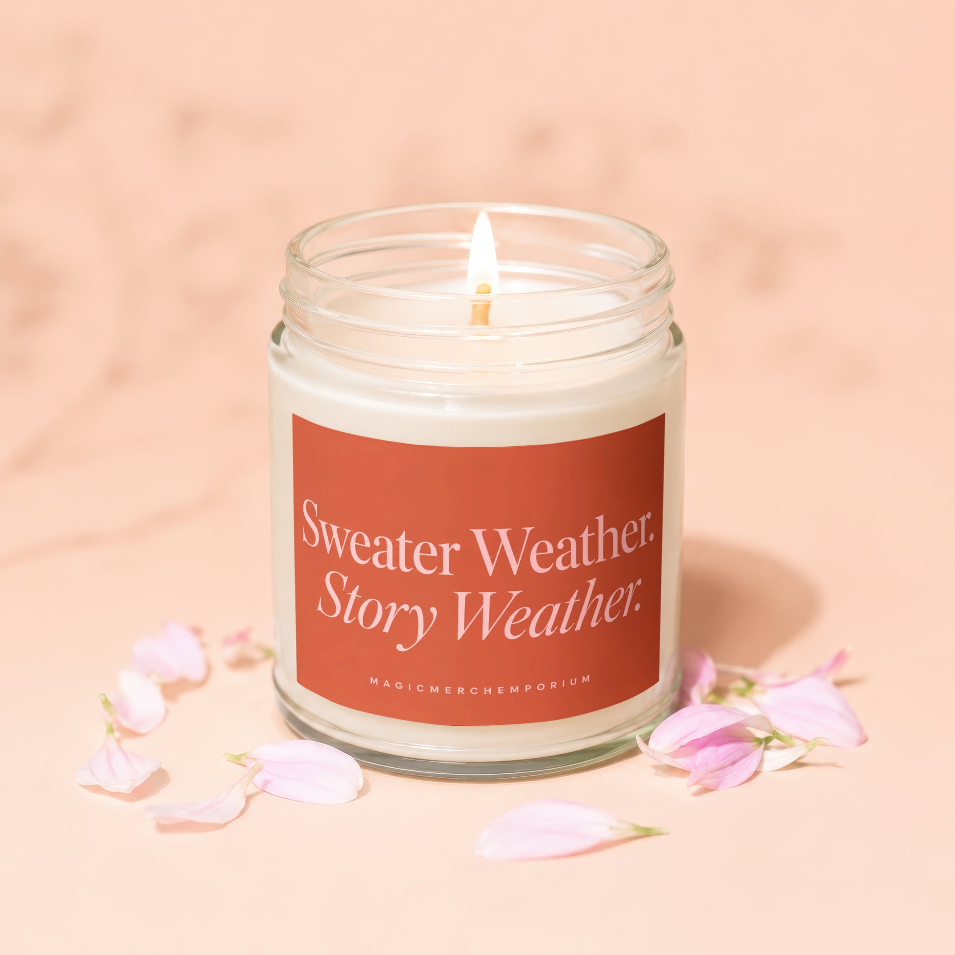 Lit candle in a jar with an orange label that reads "Sweater Weather. Story Weather."