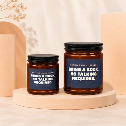 Two amber glass candles with black lids, featuring dark blue labels that read "Reading Night Rules: Bring a Book. No Talking Required."