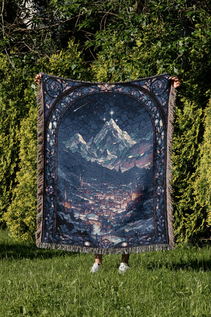 A person is holding up a large, intricately designed tapestry depicting a mountainous landscape with a starry night sky.