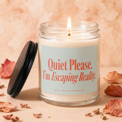 Lit glass candle with black lid, reading "Quiet Please. I'm Escaping Reality."