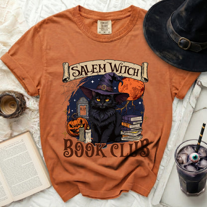 Orange t-shirt with a Halloween graphic featuring a black cat, books, pumpkin, and the text "Salem Witch Book Club".