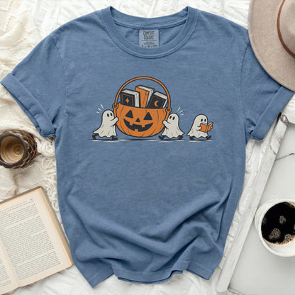 Three ghosts carry a jack-o'-lantern bucket filled with books.