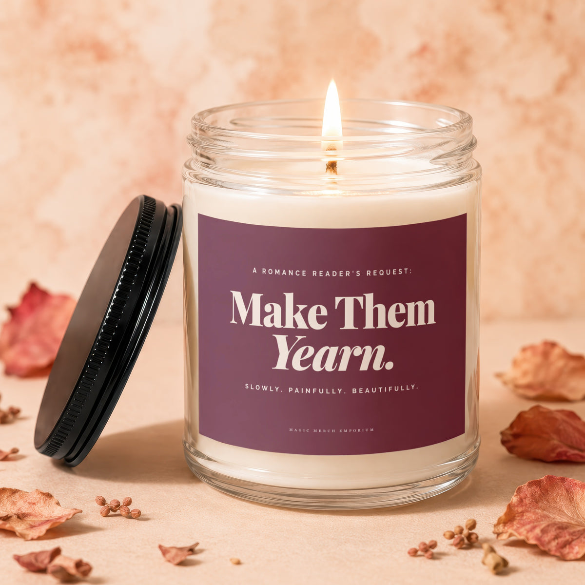 Lit candle in glass jar with "Make Them Yearn." text and dried flowers.