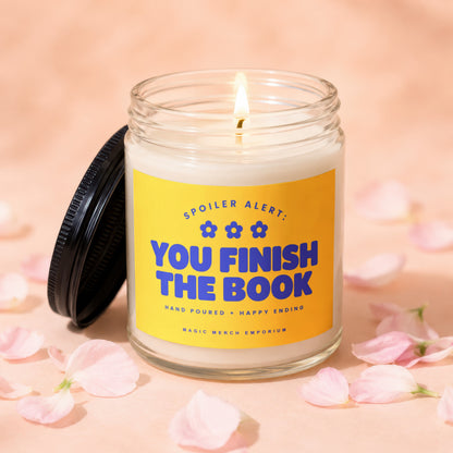 Lit candle with yellow label reading "Spoiler Alert: You Finish The Book."