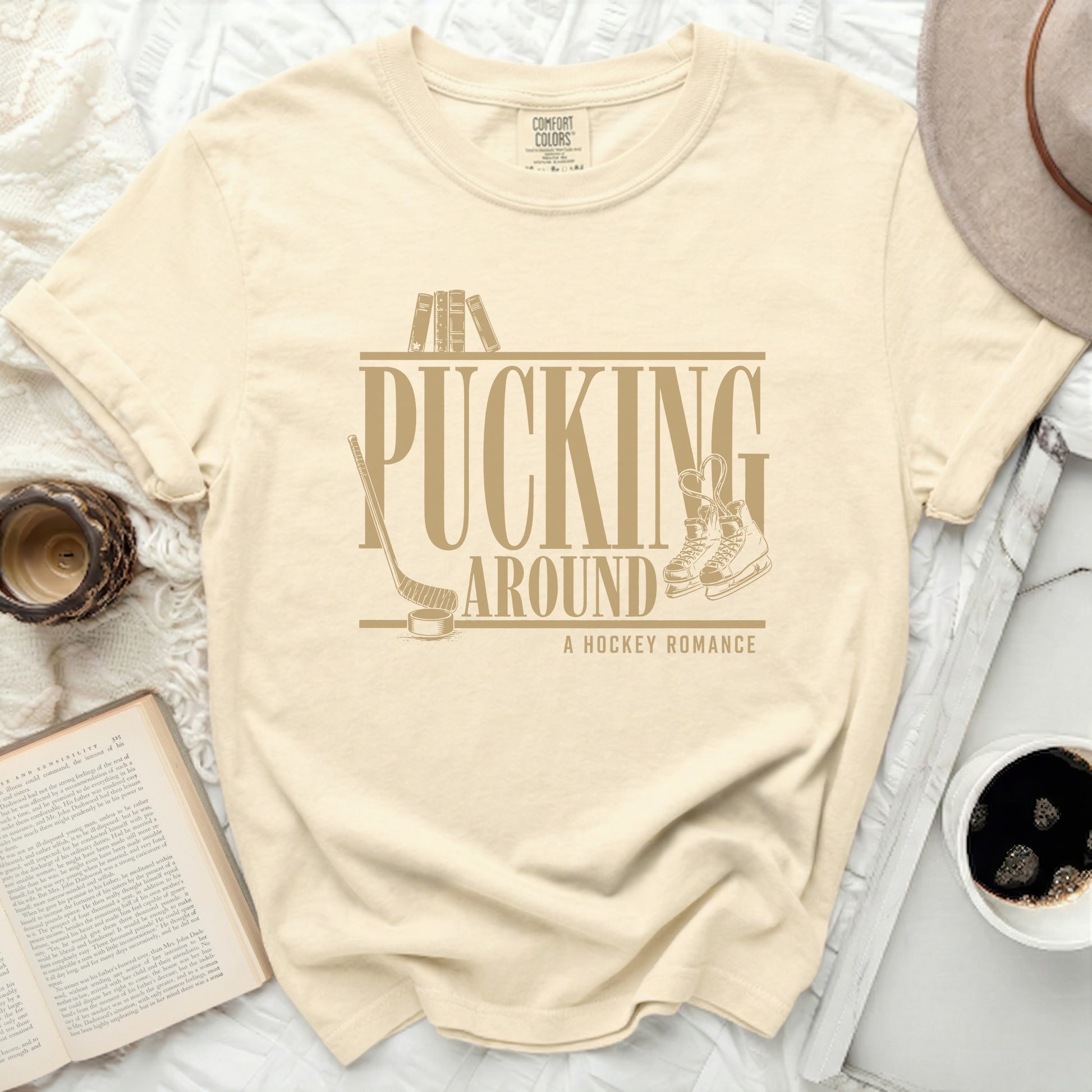 Cream t-shirt with "Pucking Around A Hockey Romance" text and hockey graphics.