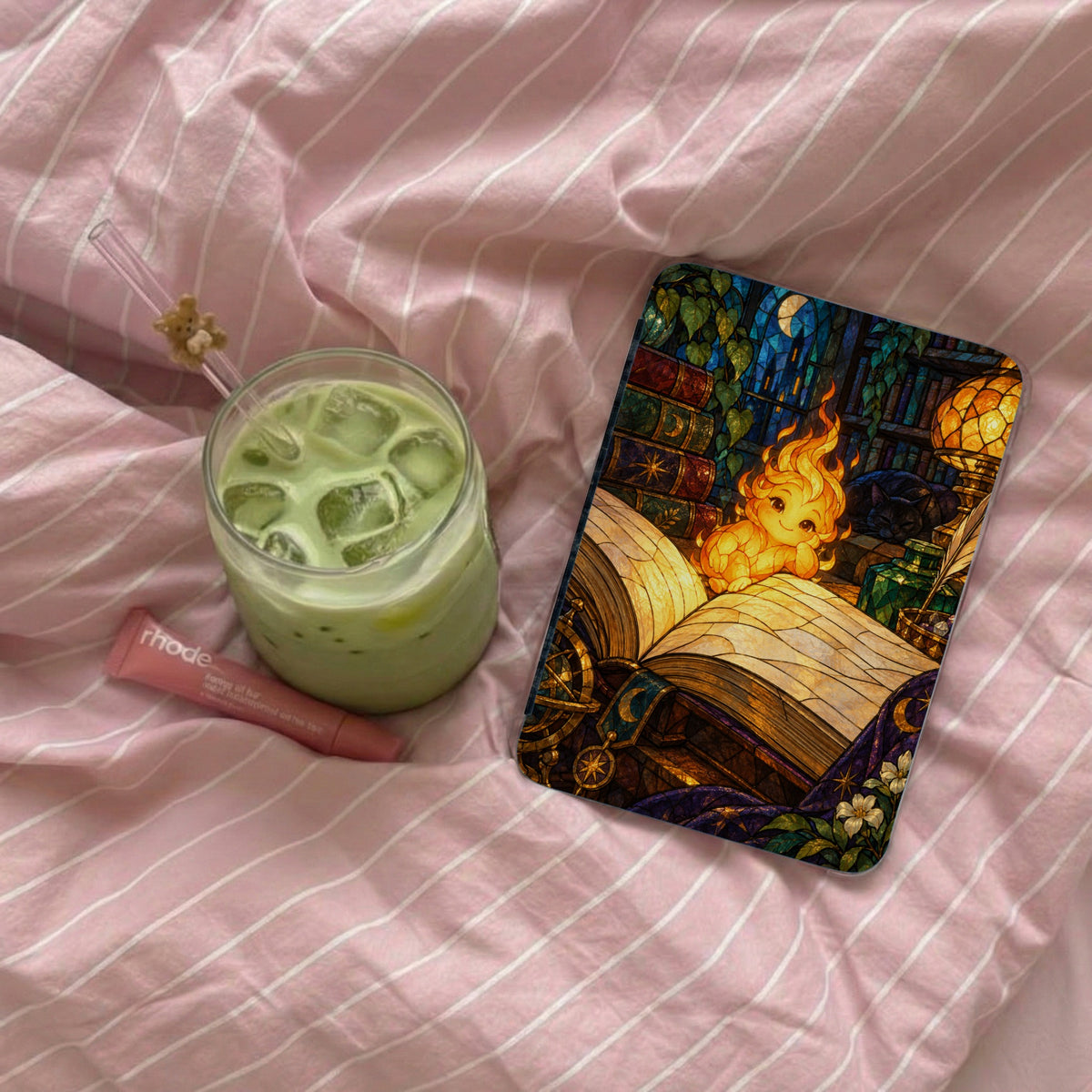 A flat lay featuring a glass of green iced drink and a phone case with a whimsical creature.