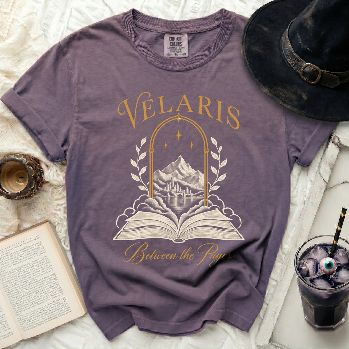Purple t-shirt with Velaris Between the Pages graphic and open book.