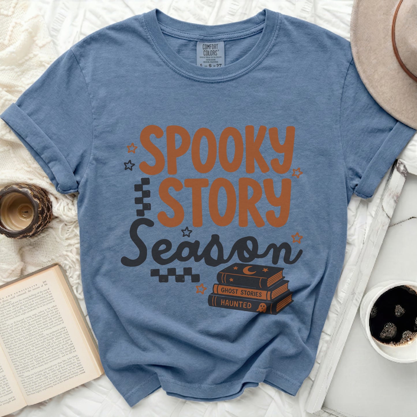 Blue t-shirt with "Spooky Story Season" text and stack of books.