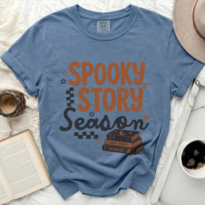 Blue t-shirt with "Spooky Story Season" text and stack of books.