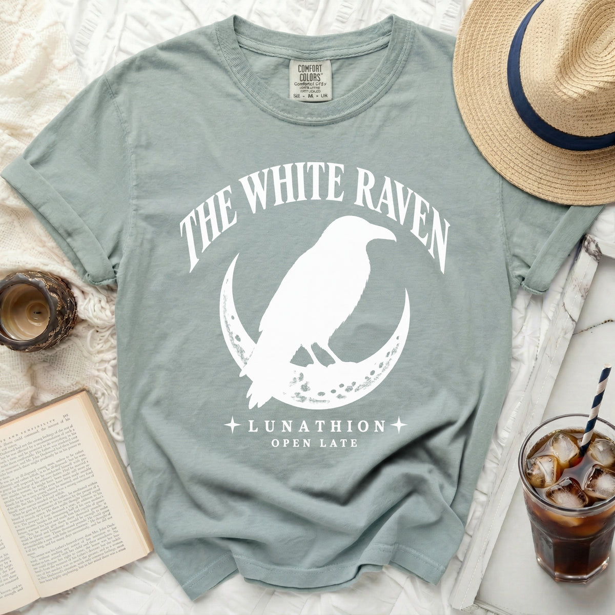 Light blue t-shirt with "The White Raven" and raven on moon graphic.