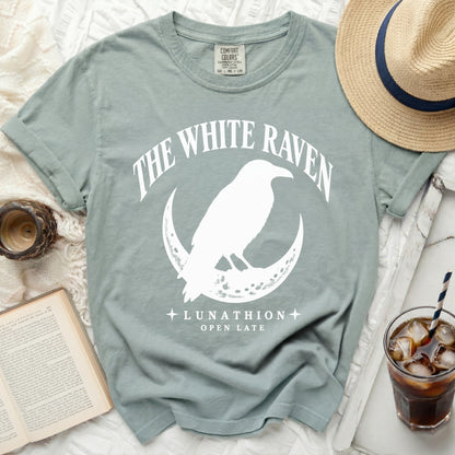Light blue t-shirt with "The White Raven" and raven on moon graphic.