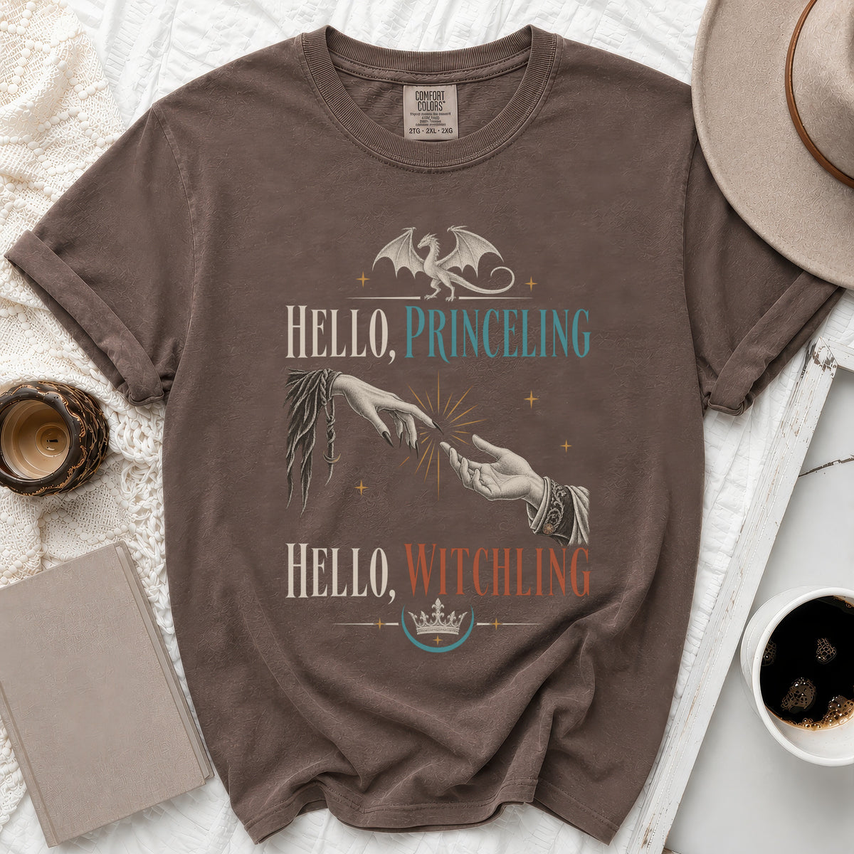 Brown t-shirt with "Hello, Princeling" and "Hello, Witchling" text, dragon, and hands.