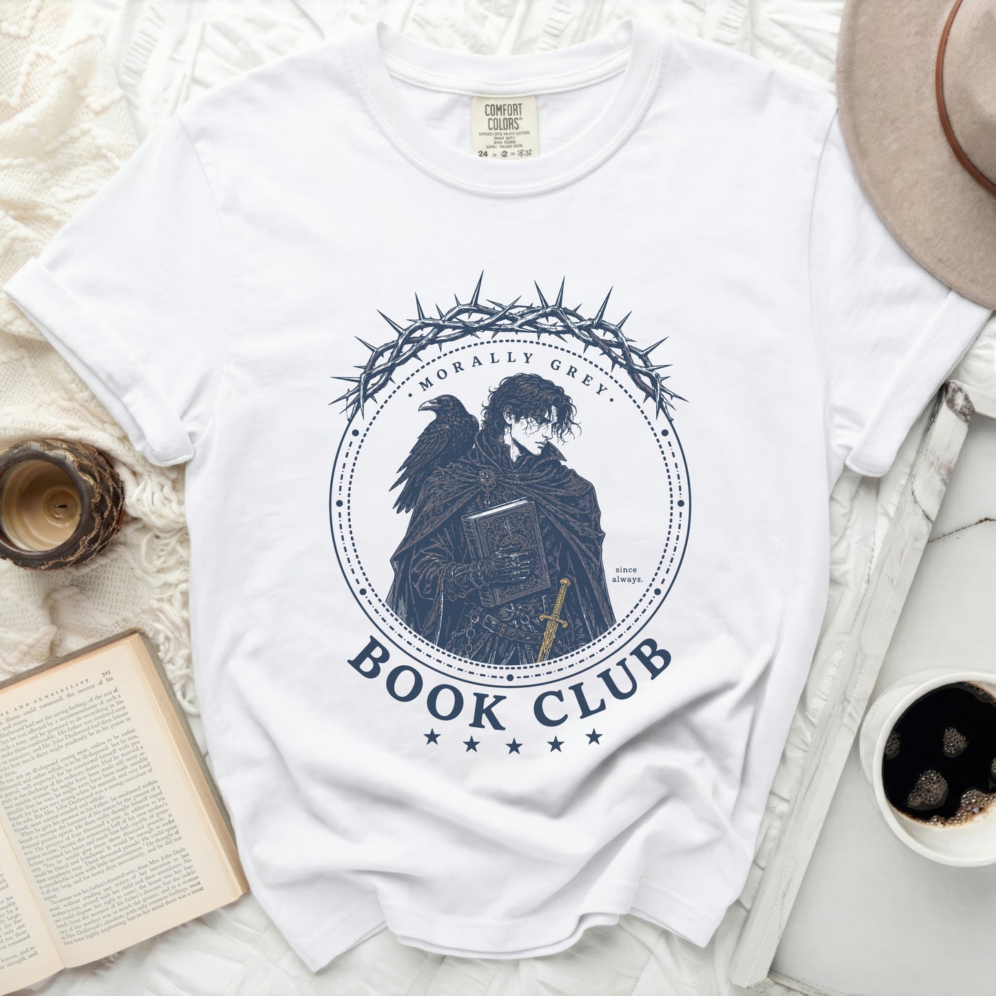 White t-shirt with a dark circular graphic of a raven, thorns, and a book.