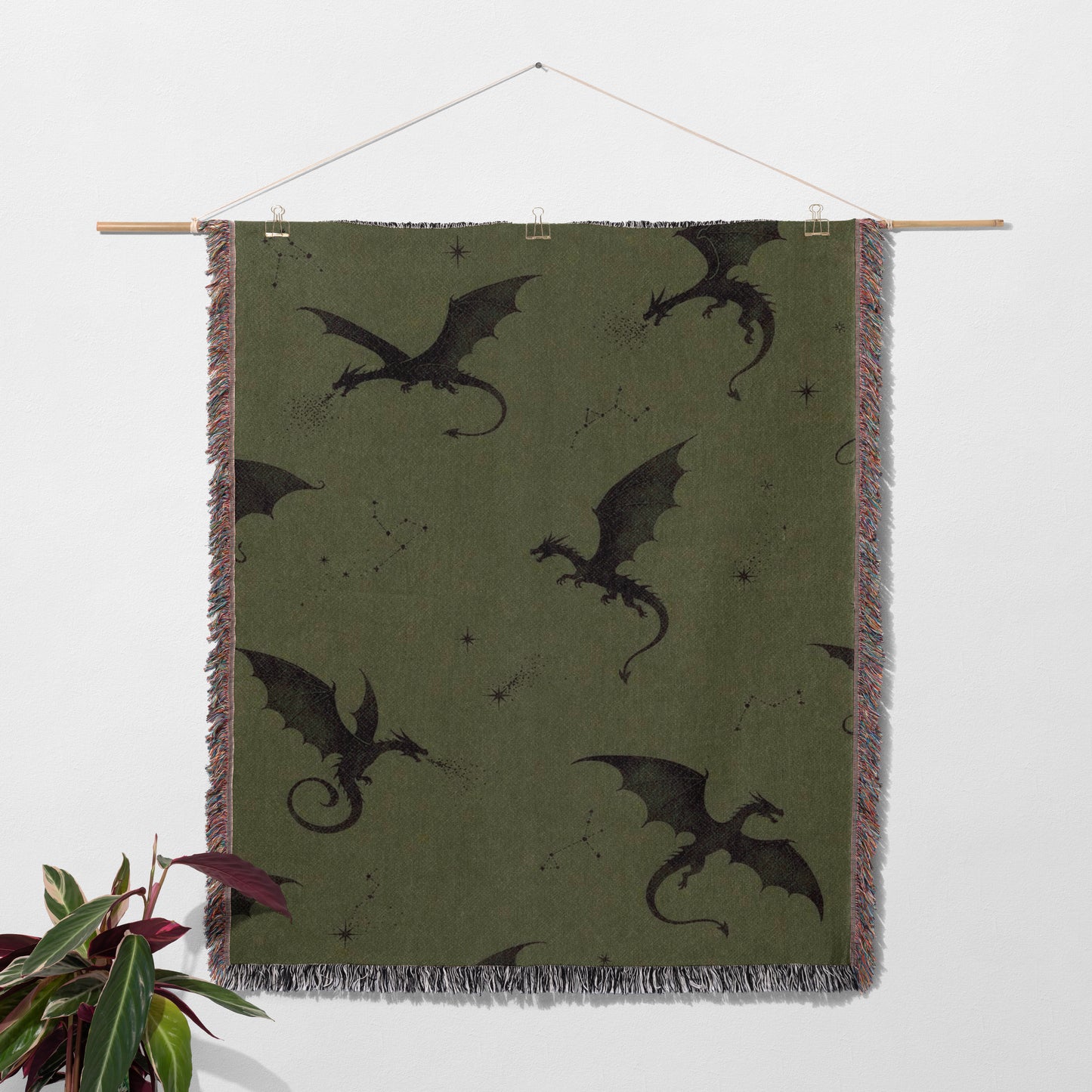a large green blanket with black dragon silhouettes on it, hanging on a wall.
