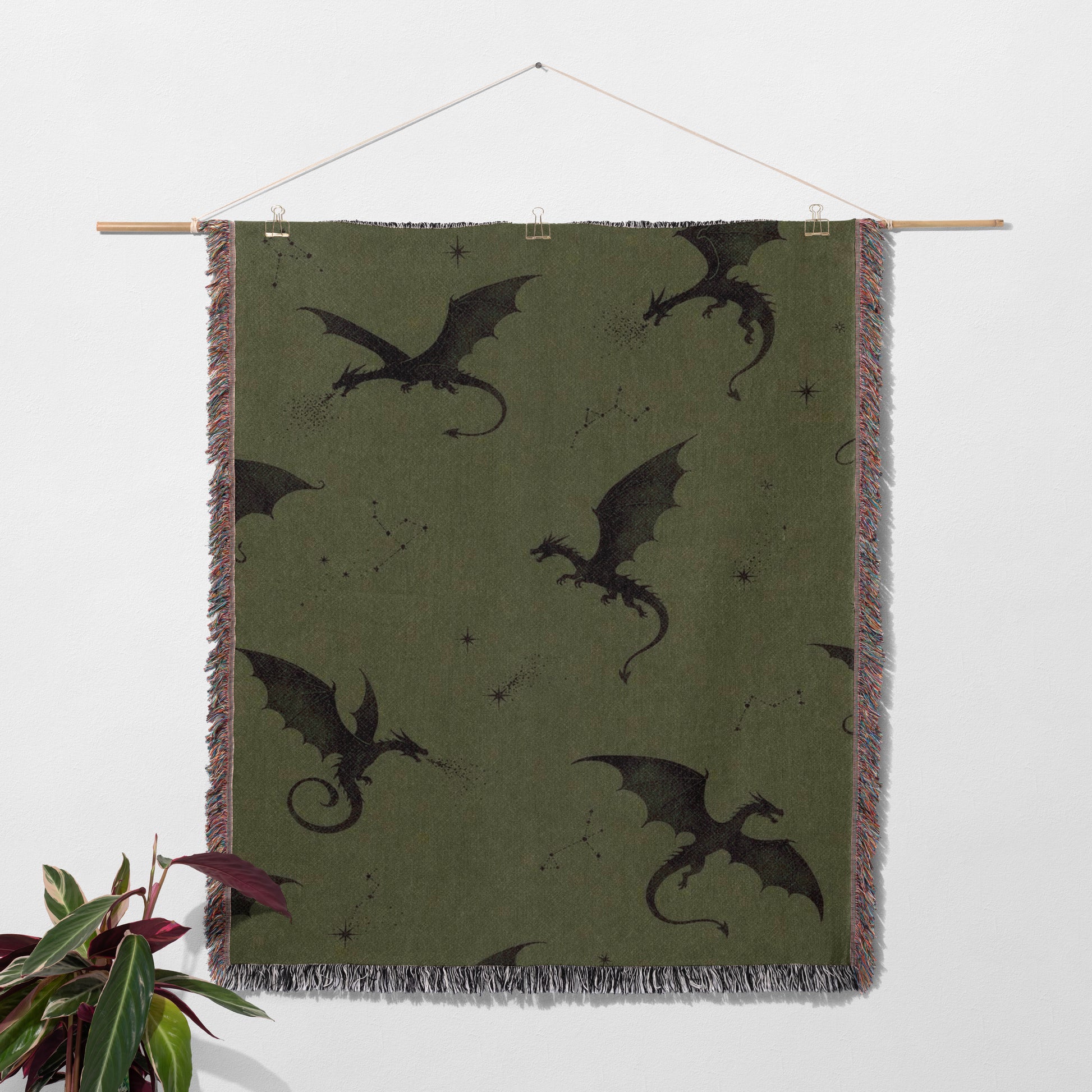 a large green blanket with black dragon silhouettes on it, hanging on a wall.