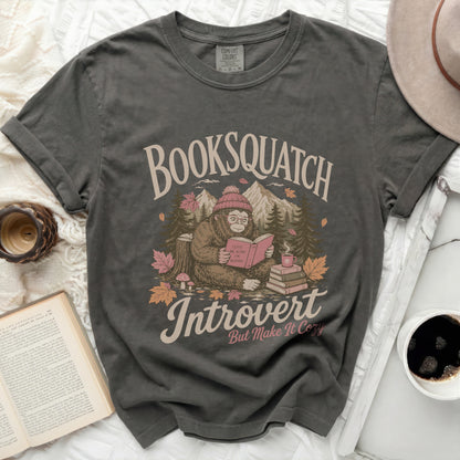 Graphic t-shirt with a Bigfoot reading a book, "Booksquatch Introvert" text.