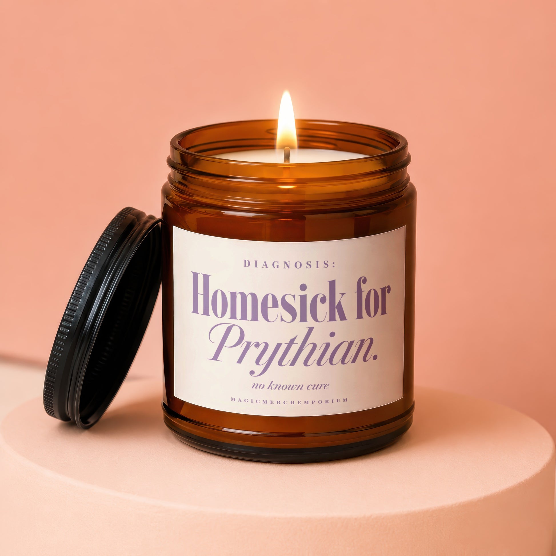 Amber glass candle with lit wick on a pink pedestal, labeled.