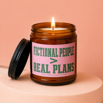 Amber jar candle with lit wick and lid beside it, reads "Fictional People > Real Plans"