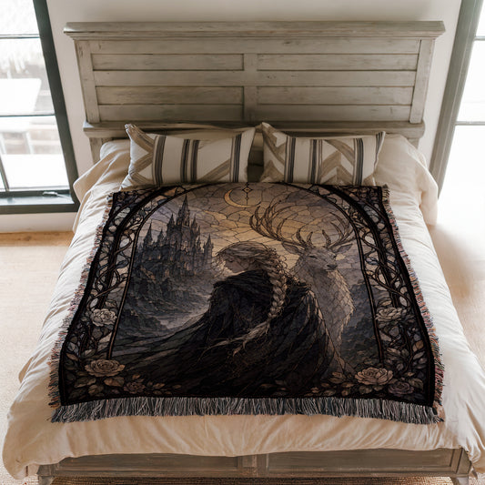 a bed with a large, intricate tapestry or blanket on it. The blanket has a detailed design depicting a woman with long hair and a castle in the background. The bed is set against a white wall, and there are pillows on the bed.