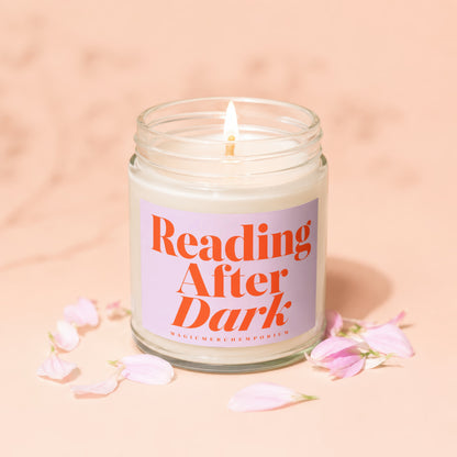 Lit "Reading After Dark" candle surrounded by pink flower petals.