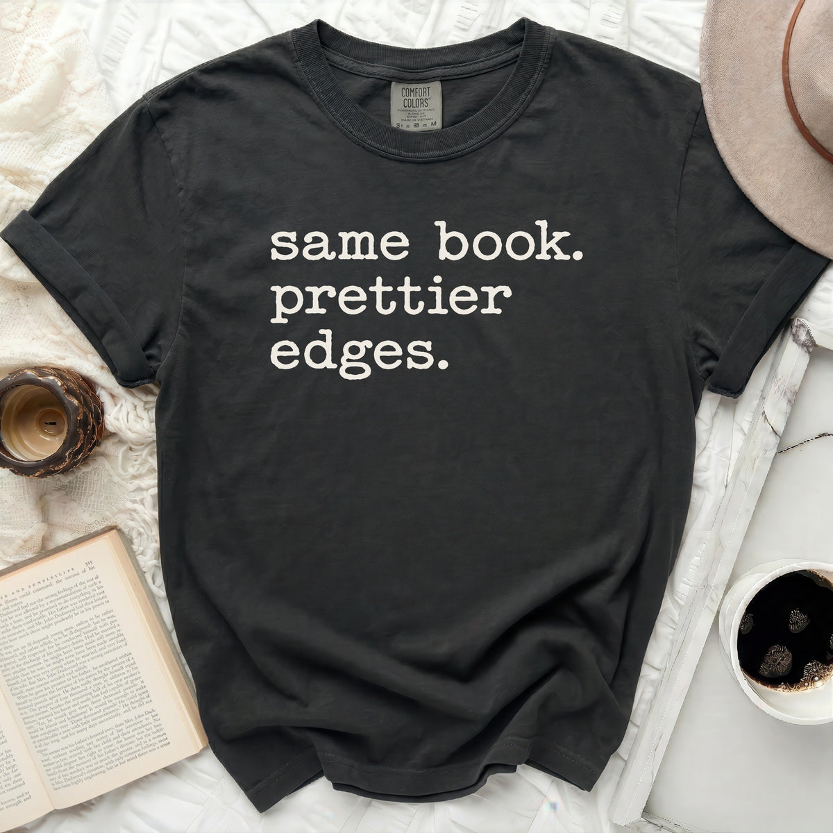 Dark t-shirt with white text "same book. prettier edges."
