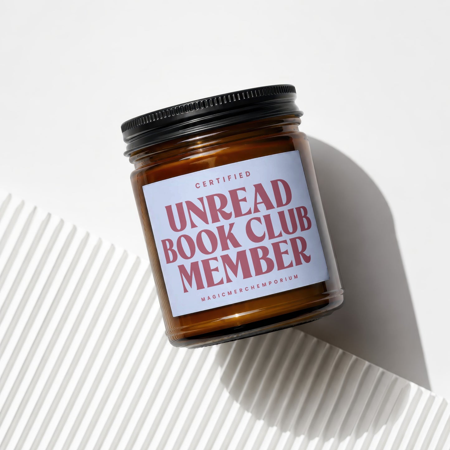 Amber glass candle labeled "Certified Unread Book Club Member".