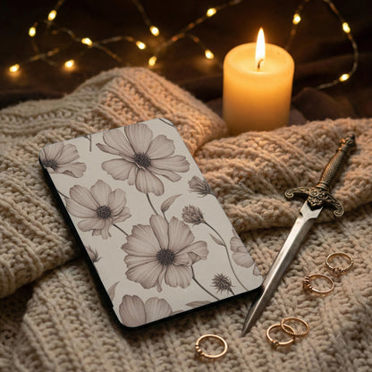 Notebook with floral pattern, candle, dagger, and rings on a knitted blanket.
