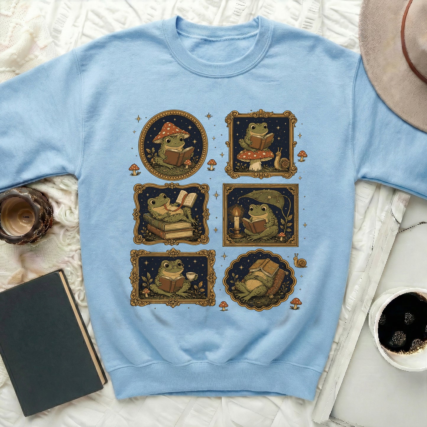Light blue sweatshirt featuring a collage of illustrated frogs reading books and mugs.