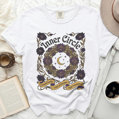 White t-shirt with purple and gold floral wreath, moon, stars, and text.
