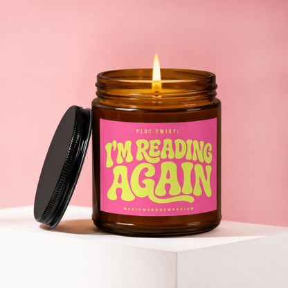 Amber glass candle with pink label reading "PLOT TWIST: I'M READING AGAIN".