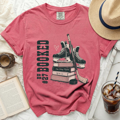 Book t-shirt with hockey skates, stick, and puck on books.