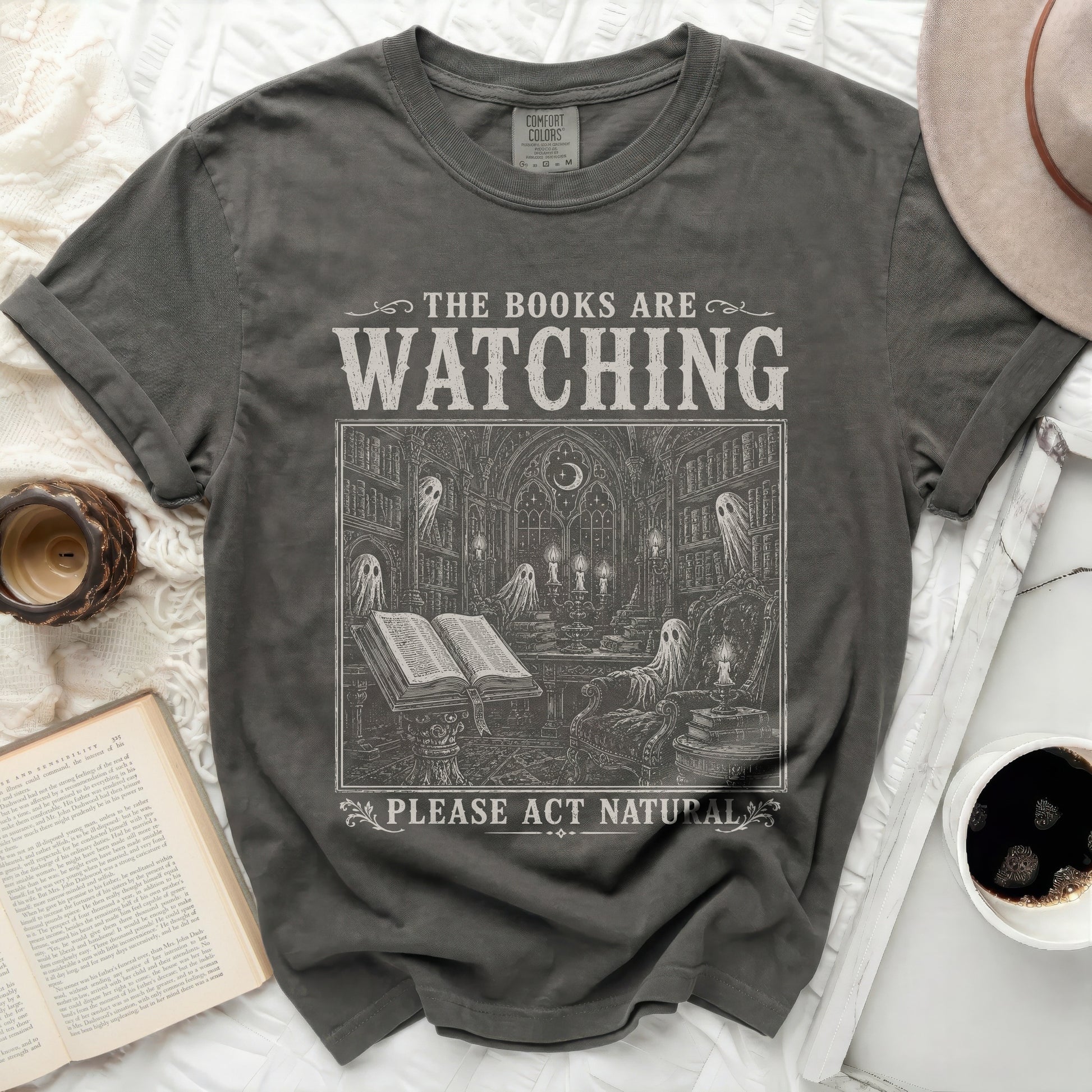 Dark grey t-shirt with "The Books Are Watching" and gothic library illustration.