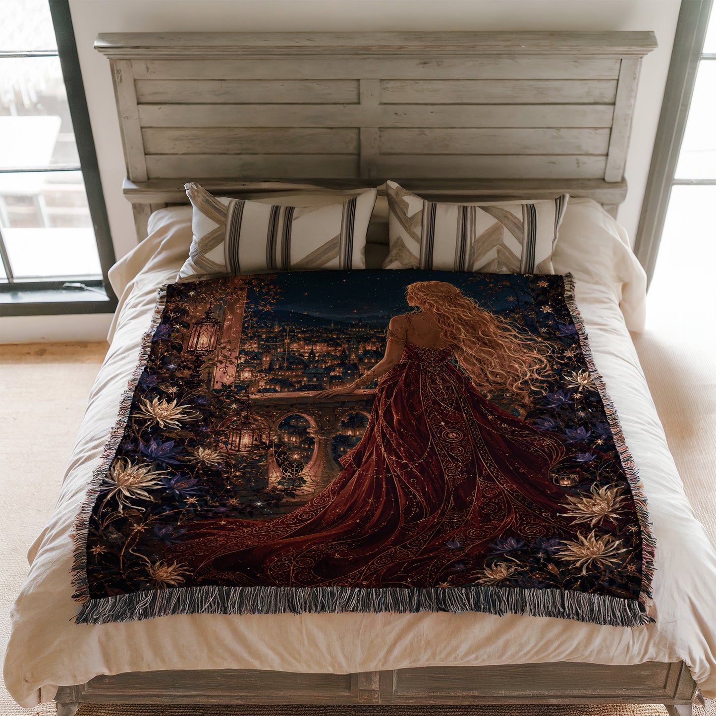 a large bed with a decorative blanket that depicts a woman in a flowing red dress standing in front of a cityscape at night.