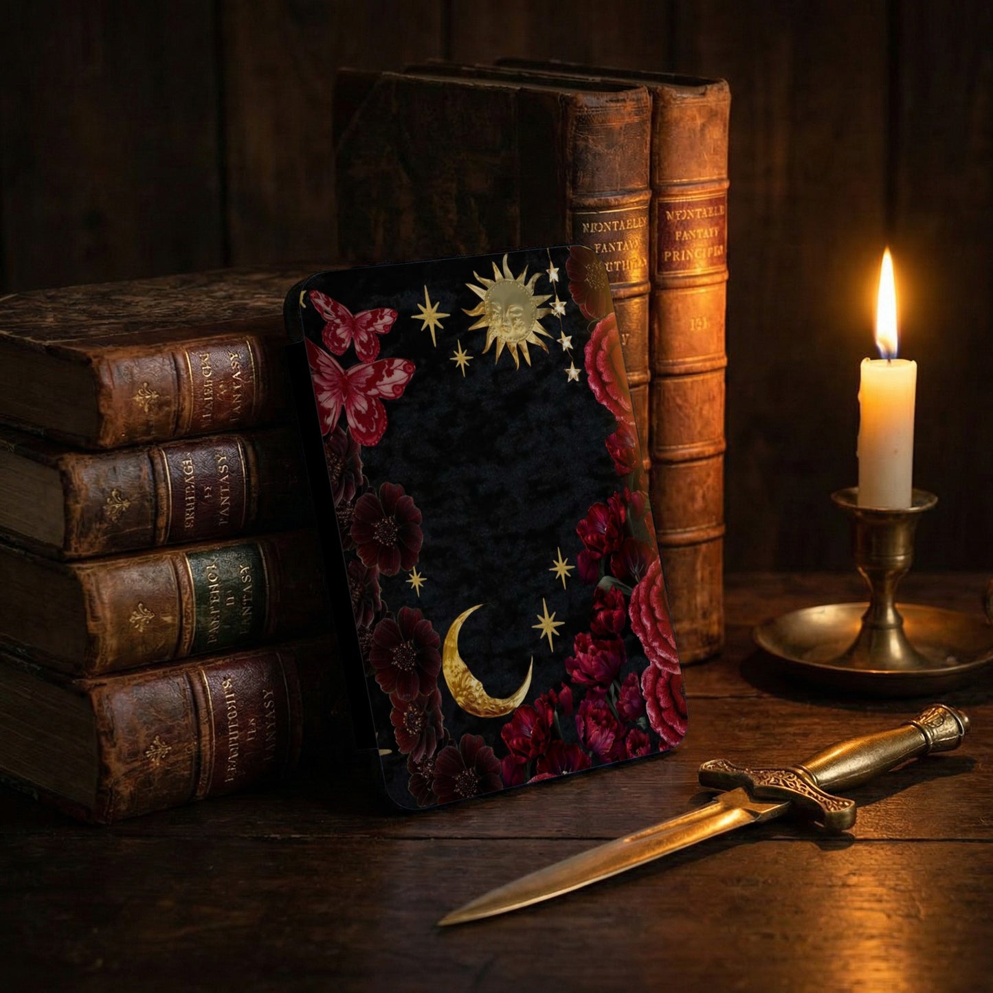 Black velvet surface with celestial and floral motifs, old books, candle, and dagger.