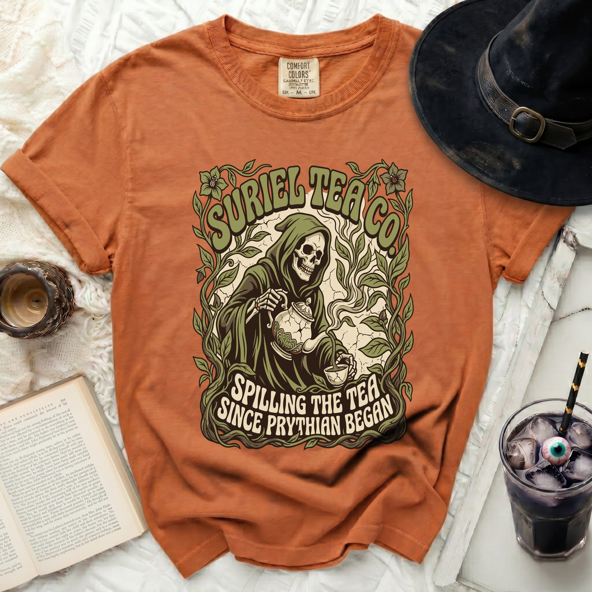 Orange t-shirt with a Grim Reaper graphic spilling tea, text reads "Suriel Tea Co. Spilling The Tea Since Phrythian Began."