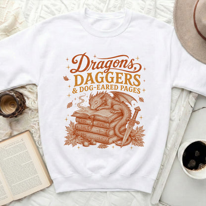 White sweatshirt with "Dragons Daggers & Dog-Eared Pages" and dragon illustration.