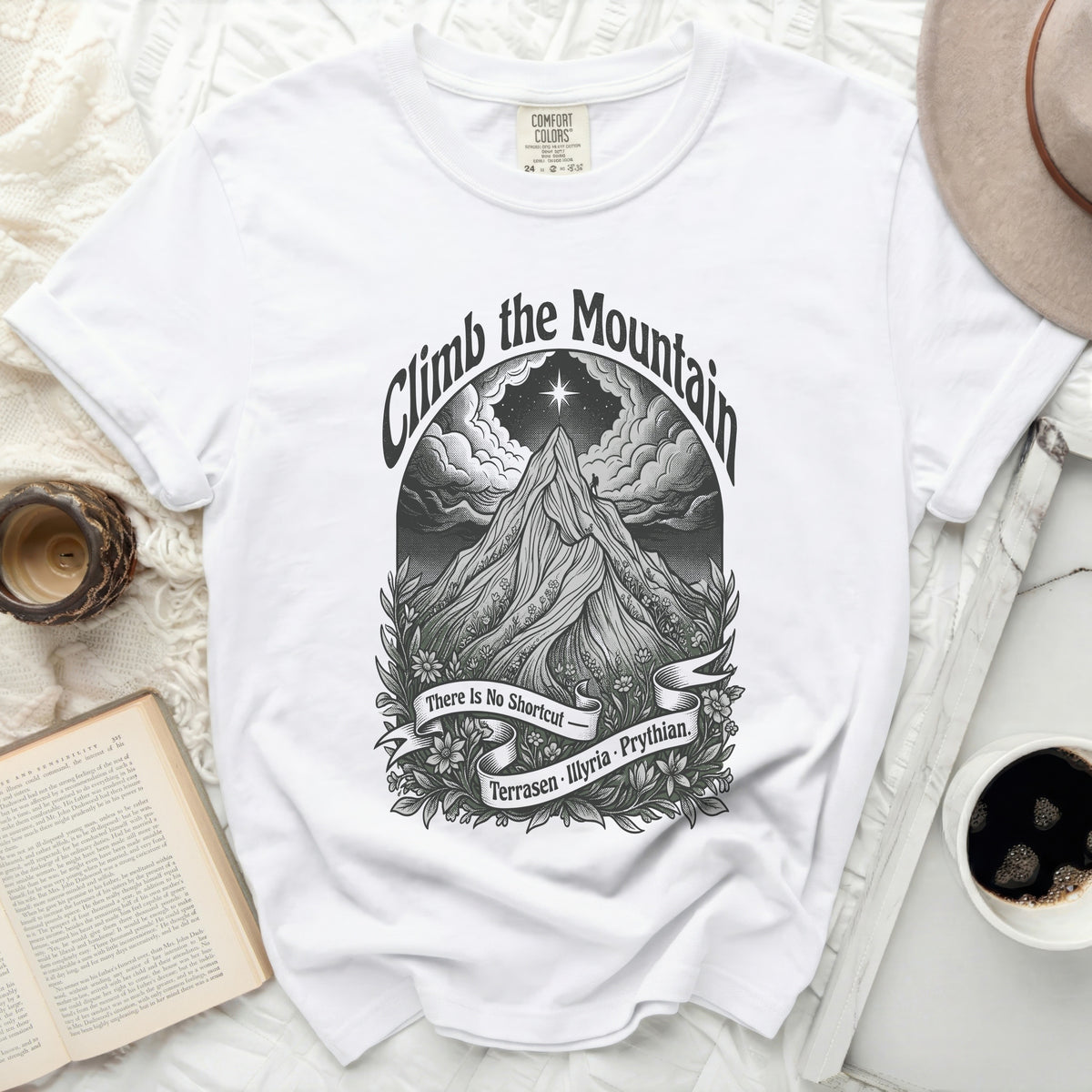 White t-shirt with "Climb the Mountain" art featuring a mountain climber.