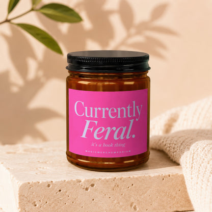 Candle with pink label reading "Currently Feral. it's a book thing."