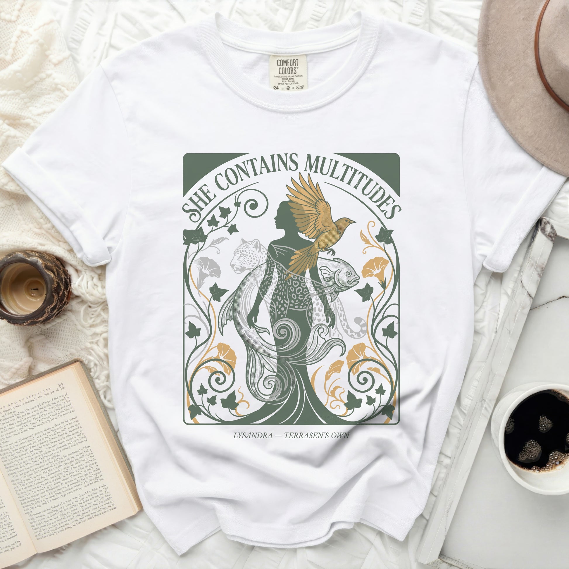 White t-shirt with "She Contains Multitudes" and mythical creatures design.
