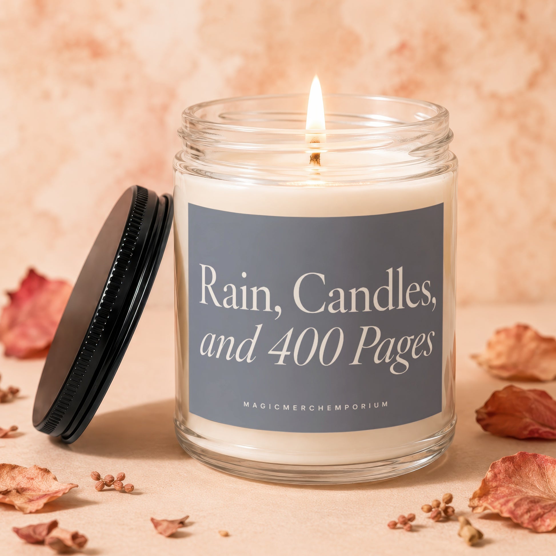 Scented candle with lit wick, black lid, and label reading "Rain, Candles, and 400 Pages".
