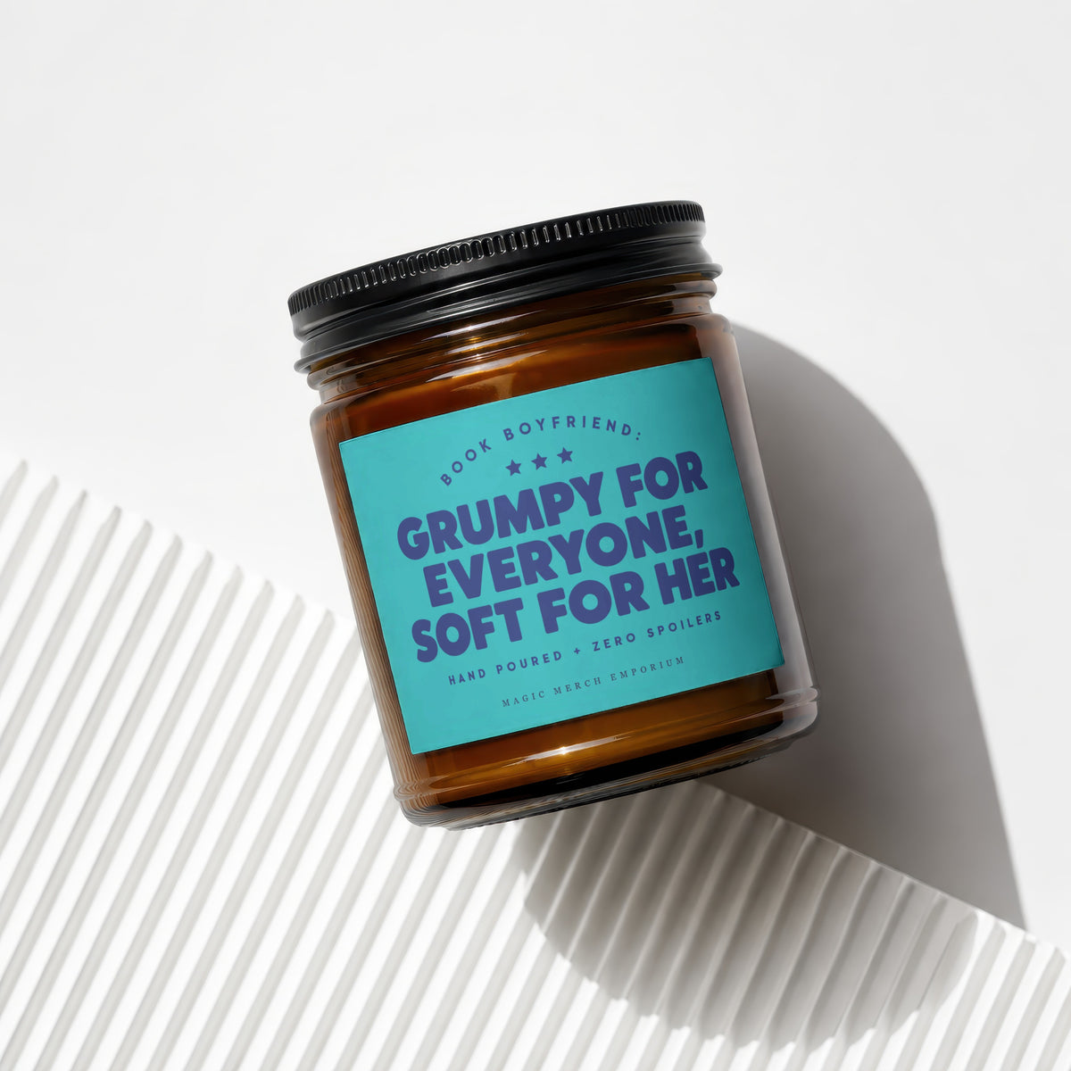 Amber candle with a teal label reading "Book Boyfriend: Grumpy for Everyone, Soft for Her."