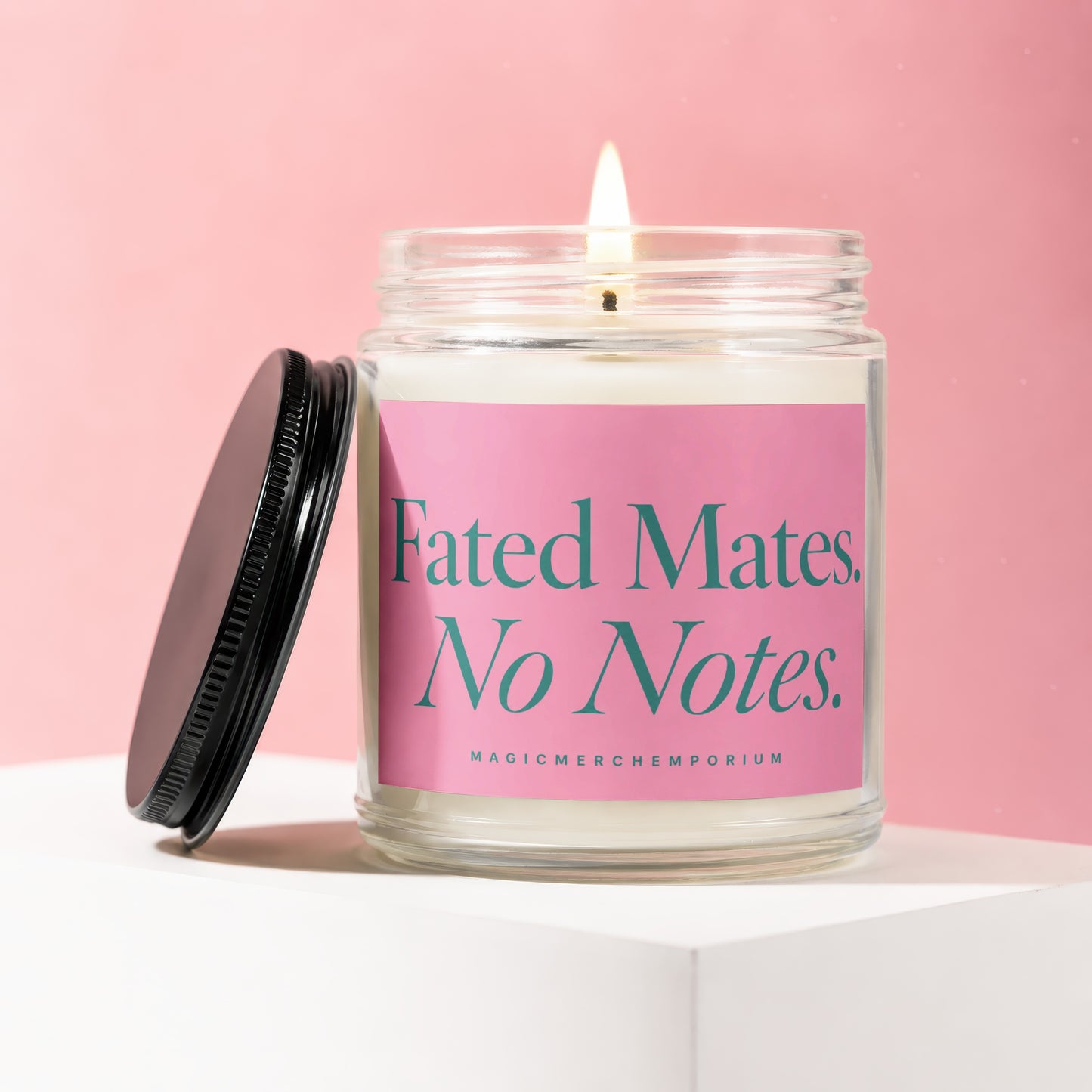 Glass candle with lit wick and black lid, on pink background. Text: "Fated Mates. No Notes."